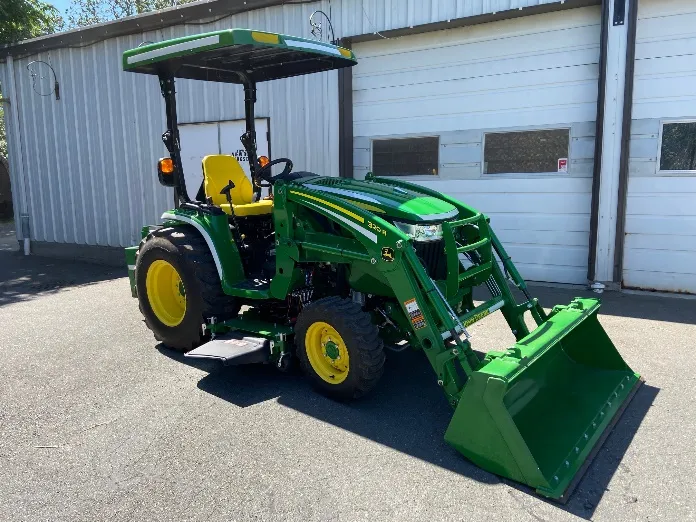 Front-quarter view of the new 2021 John Deere tractor parked in front of service bays
