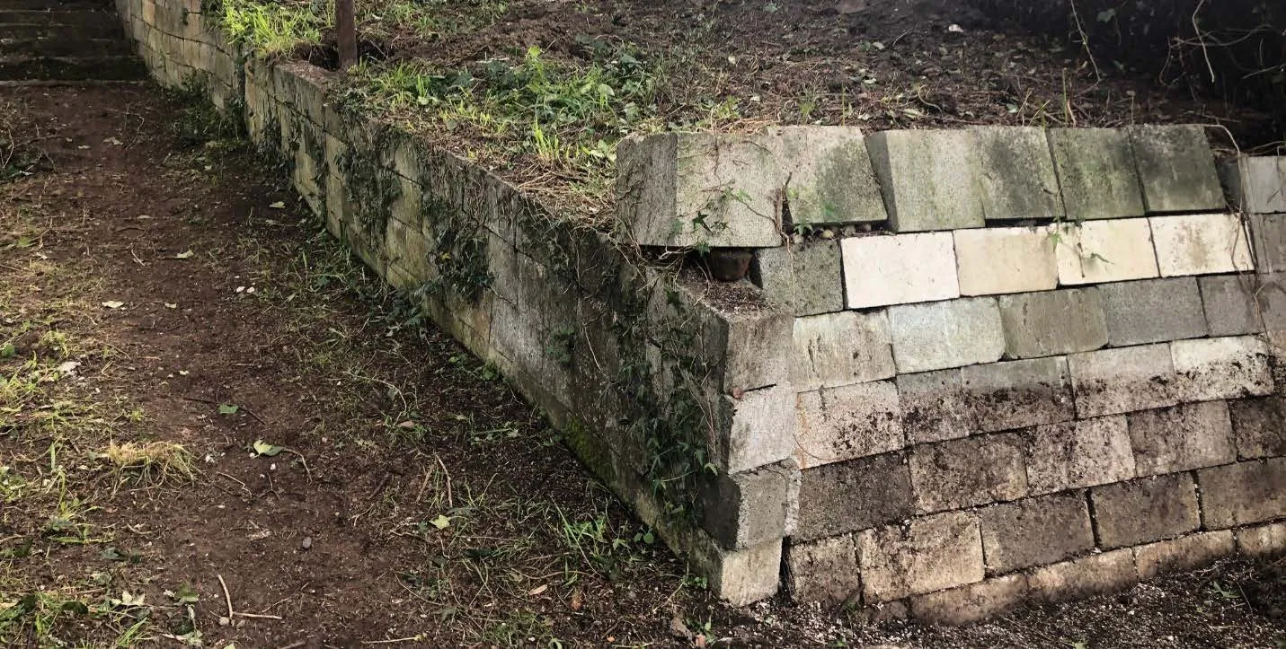Photograph showing a deteriorating concrete block retaining wall on the property