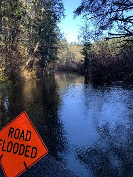 Flooded road warning sign and high water levels impacting local roads
