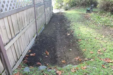 Refurbished drainage ditch running along a residential fence line on Chancellor Avenue