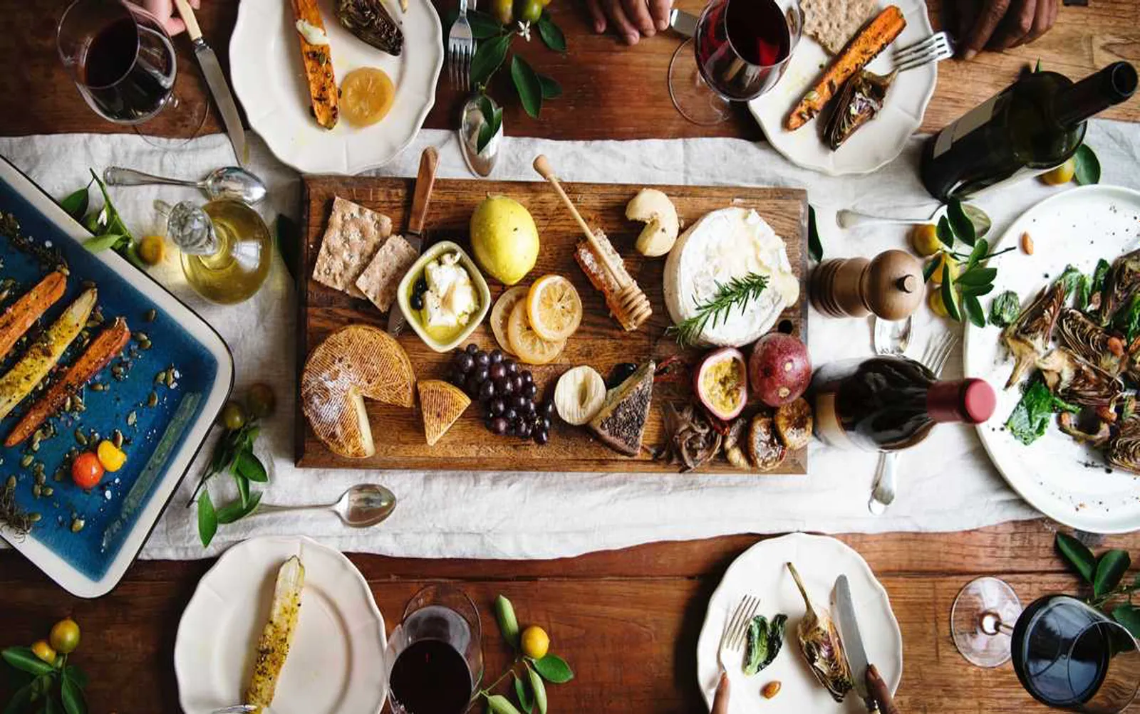 Overhead photo of a dinner table spread with food, wine, and cheese