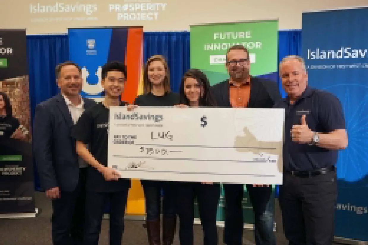 Group of six people posing with a large ceremonial check from Island Savings for $15,000 to "LUG"