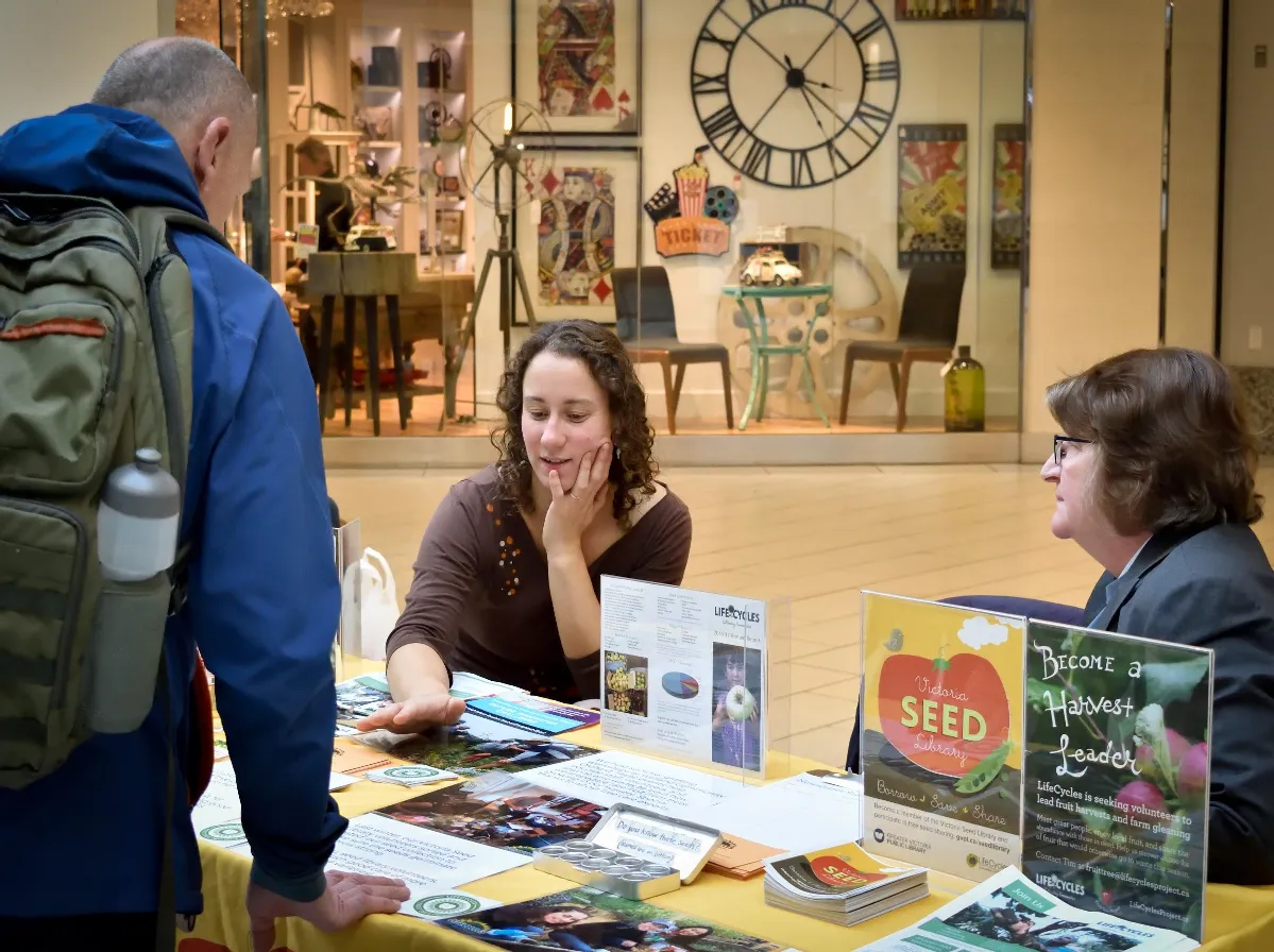 People at an information booth for the Victoria Seed Library and "Become a Harvest Leader" program