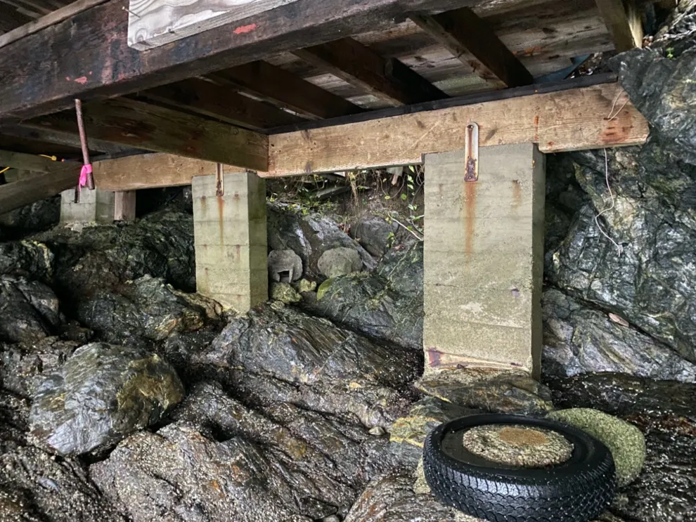 Rear support structures underneath the boathouse with a tire in the foreground