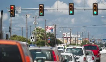 photograph of traffic signal lights over a busy multi-lane intersection