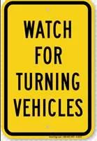 Yellow warning sign displaying "WATCH FOR TURNING VEHICLES"