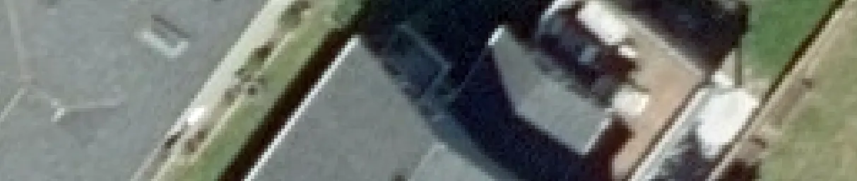 Aerial view crop showing a portion of a residential roof and adjacent lawn