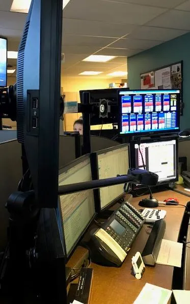 Overview of a dispatch workstation showing several computer displays and communication equipment