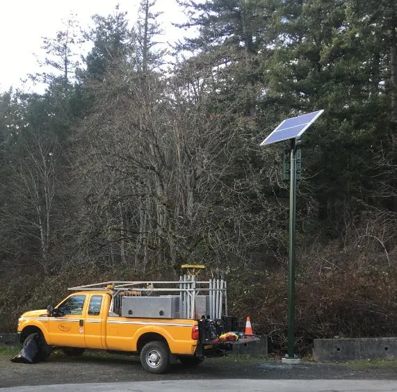 A solar-powered light pole installed along Highland Road next to a service vehicle