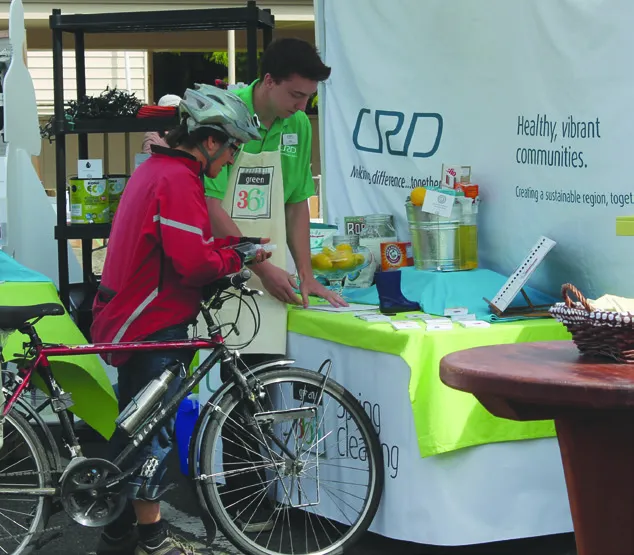 A CRD representative at an information booth speaking with a woman on a bicycle.