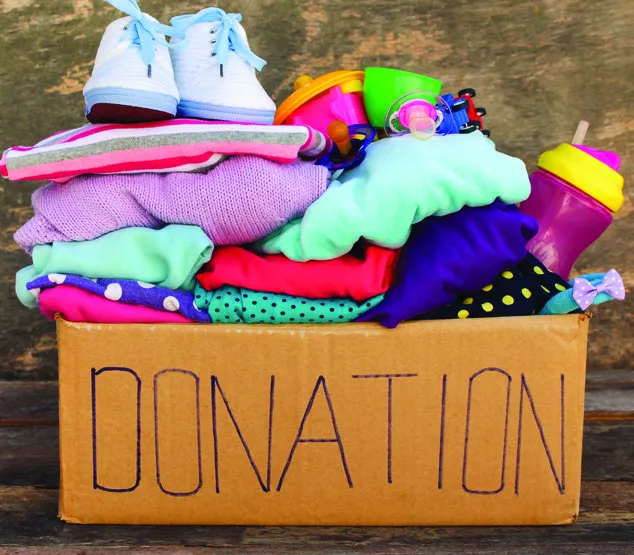 A cardboard box marked "DONATION" filled with various items like clothes and toys.