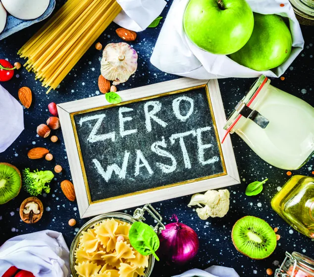 A variety of food items surrounding a small chalkboard that reads "ZERO WASTE".