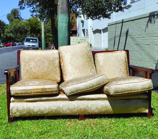 An old couch abandoned on a grassy roadside.