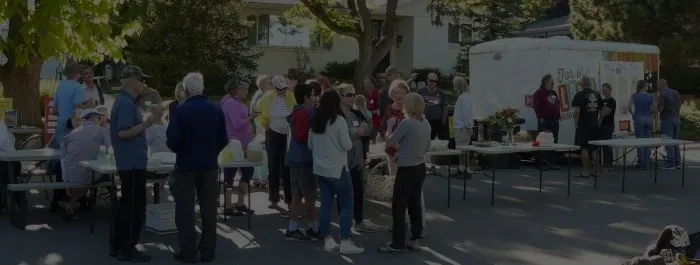 Neighbors gathering around tables with a food truck in the background