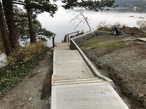 Photo of the new concrete pathway and rock retaining wall looking towards the water