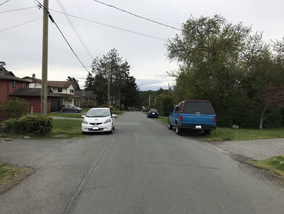 Photo depicting trucks and a car parked on the side of a road