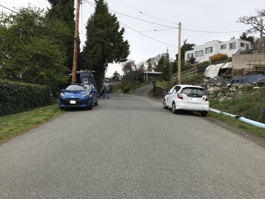 Photo depicting two cars parked on opposite sides of a road