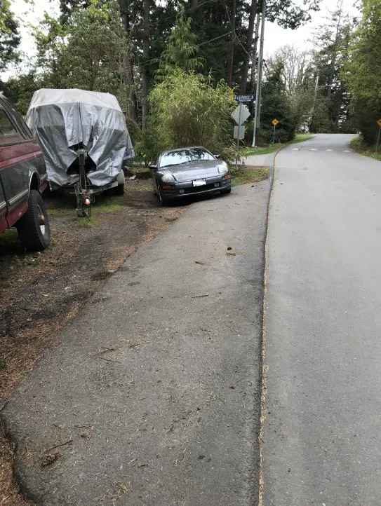 Photo depicting a red truck parked entirely off the paved roadway