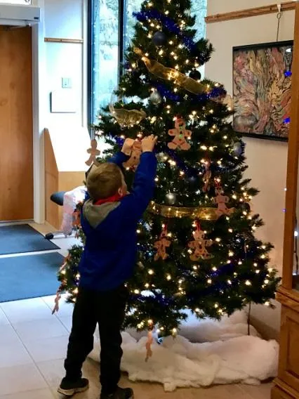 A Kindergarten student hangs his homemade decoration on the tree at Town Hall.