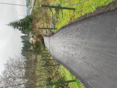 Newly paved MacLennan Trail with protective chain fencing and newly planted trees