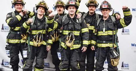 Large group of firefighters and partners posing with a service dog in the fire hall