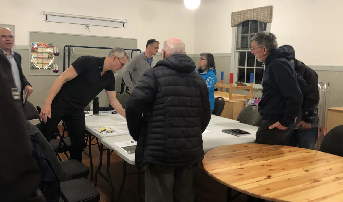 Group of participants standing around tables during a community workshop