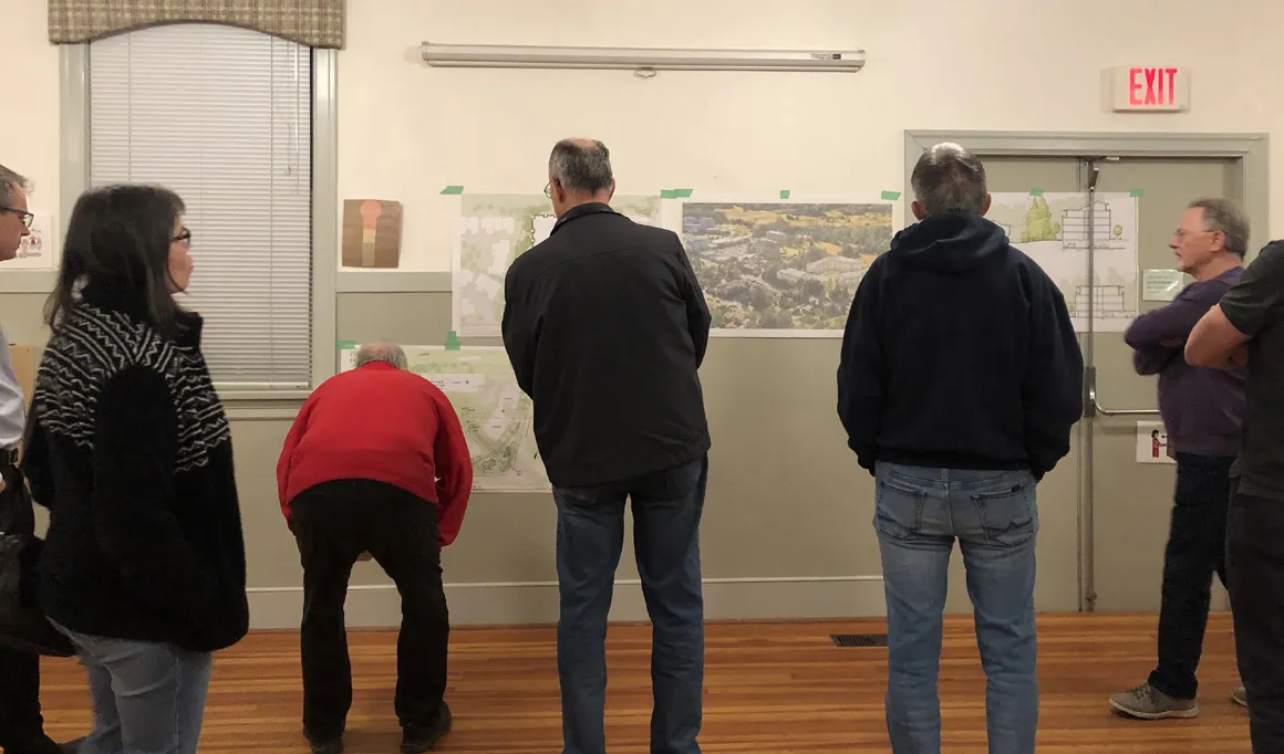 Workshop attendees viewing presentation boards pinned to a wall