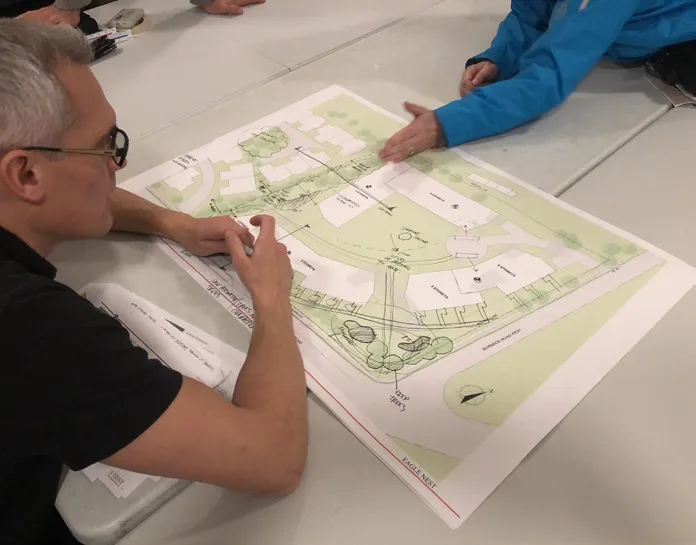 Photo from the Community Meeting Open House showing attendees standing and reviewing project display boards.
