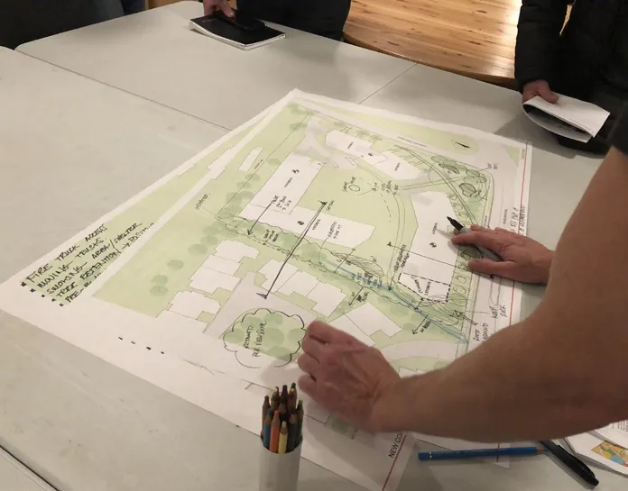 Another view of the Community Meeting Open House with residents and project team members discussing the revised plans at various stations.