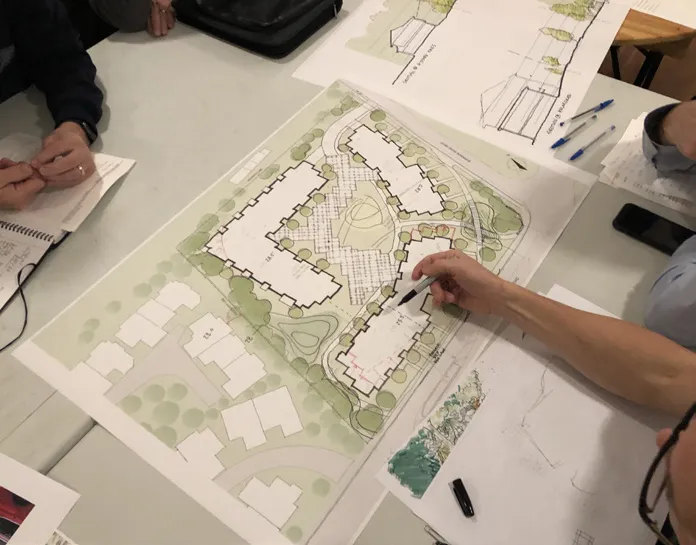 Photo of residents and project staff standing around a table, actively discussing the proposed site plan.
