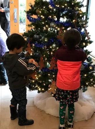 Kindergarten students hanging their homemade decoration on the tree at Town Hall