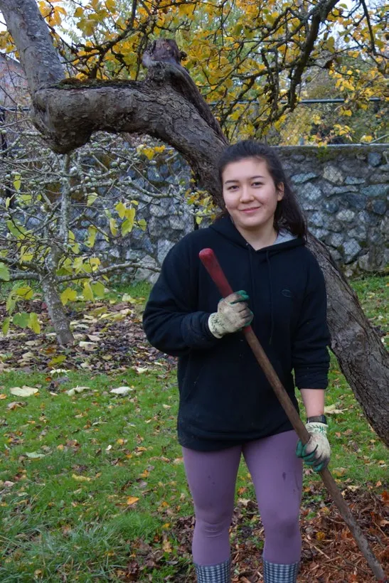 A young woman holding a shovel in a garden area