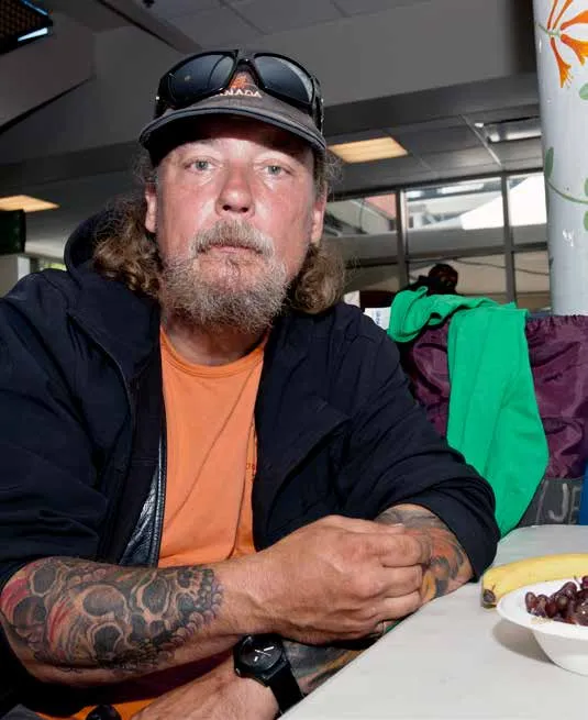 A man with a beard, tattoos, and a baseball cap sitting at a table