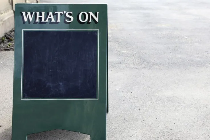Green portable sign with "WHAT'S ON" text and a chalkboard area