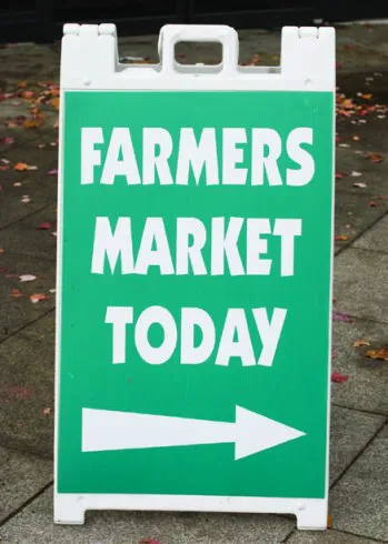 White portable sign with "FARMERS MARKET TODAY" text and a directional arrow