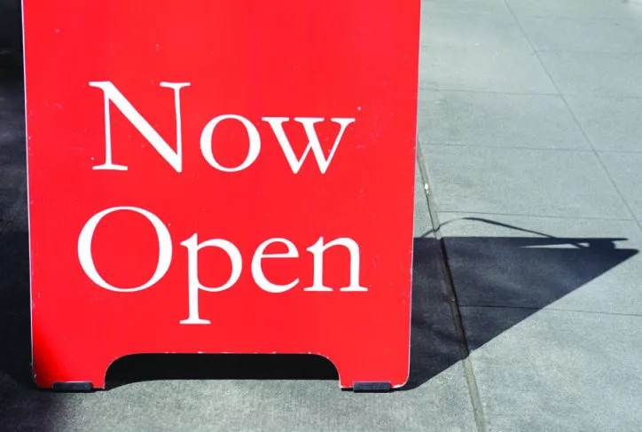 Red portable sign with "Now Open" text