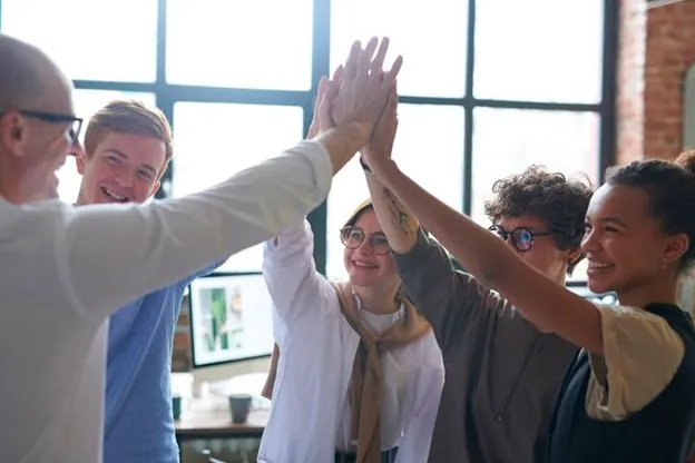 A group of five people giving a high-five together