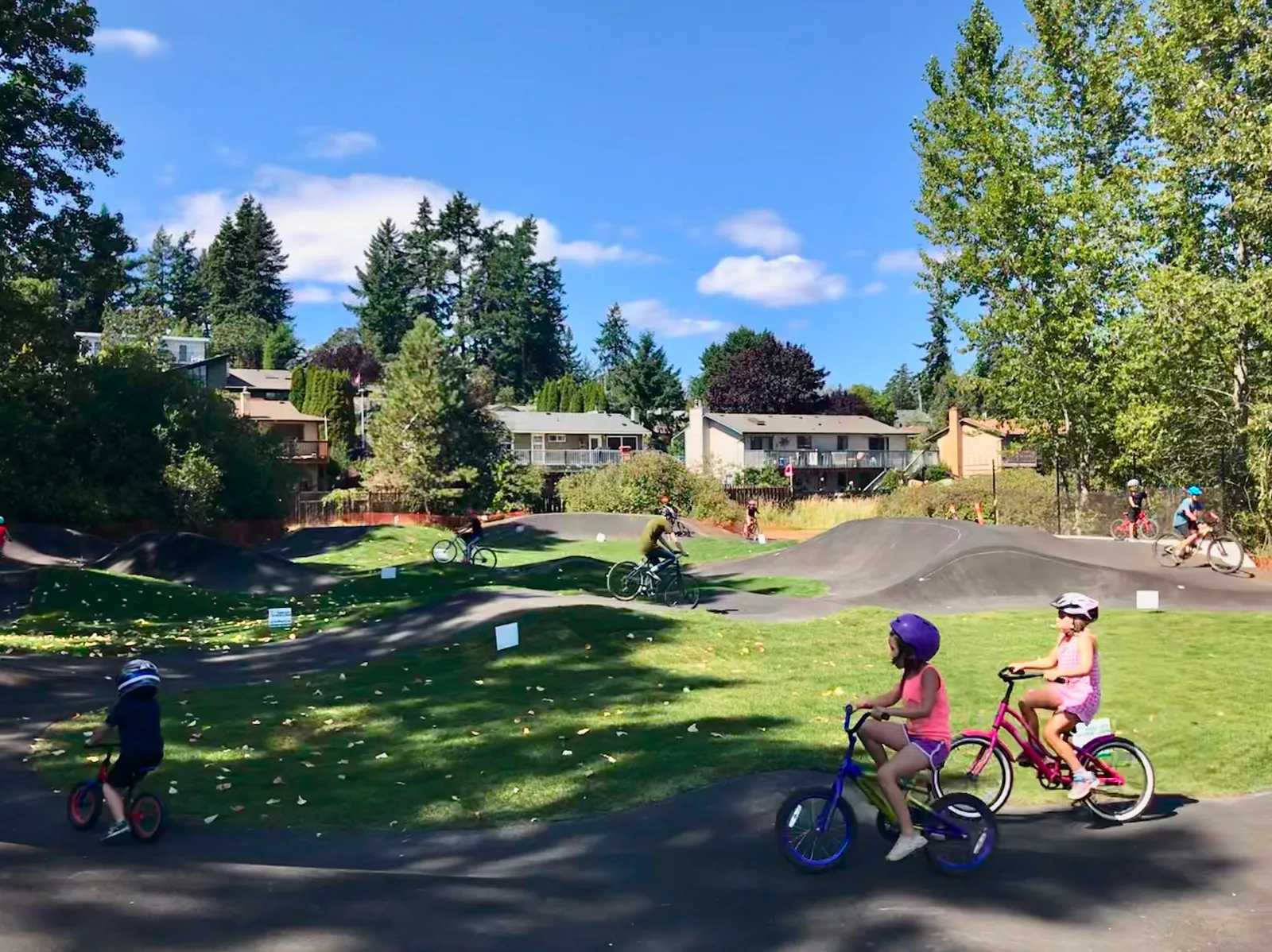 Children riding bicycles on a paved outdoor pump track