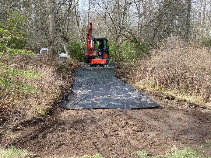 Construction equipment laying fabric for a new field pathway