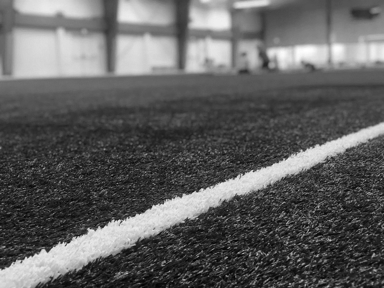 Extreme close-up of a white painted line on green synthetic sports turf