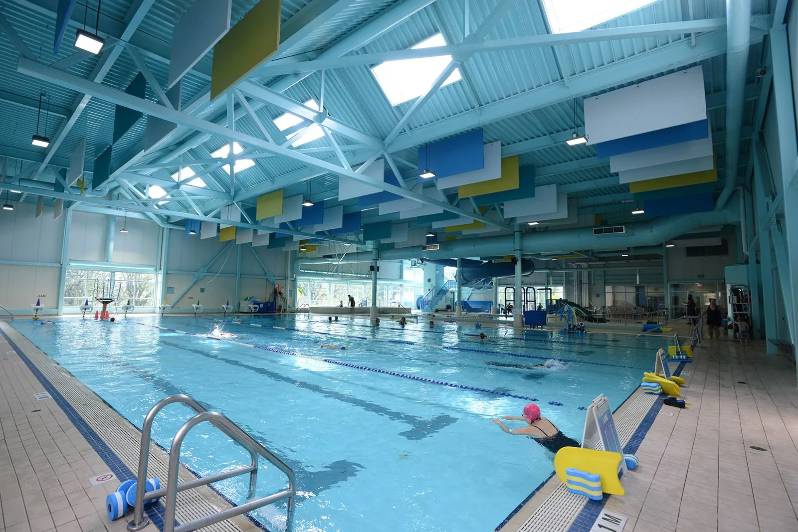 A large indoor municipal swimming pool with lap lanes and a diving board