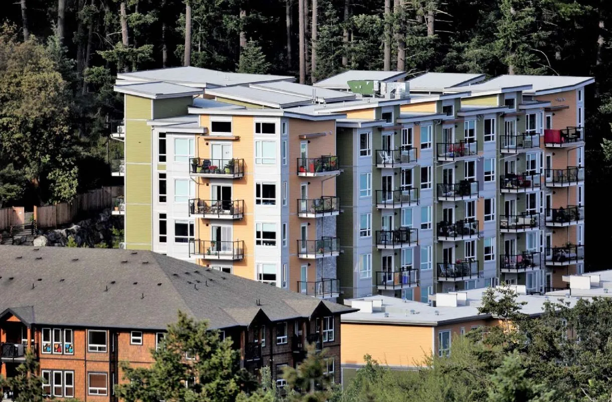 photo of a multi-unit residential building next to a forest
