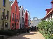 Reference photo showing a narrow pedestrian woonerf street lined with colorful, multi-story gabled houses.