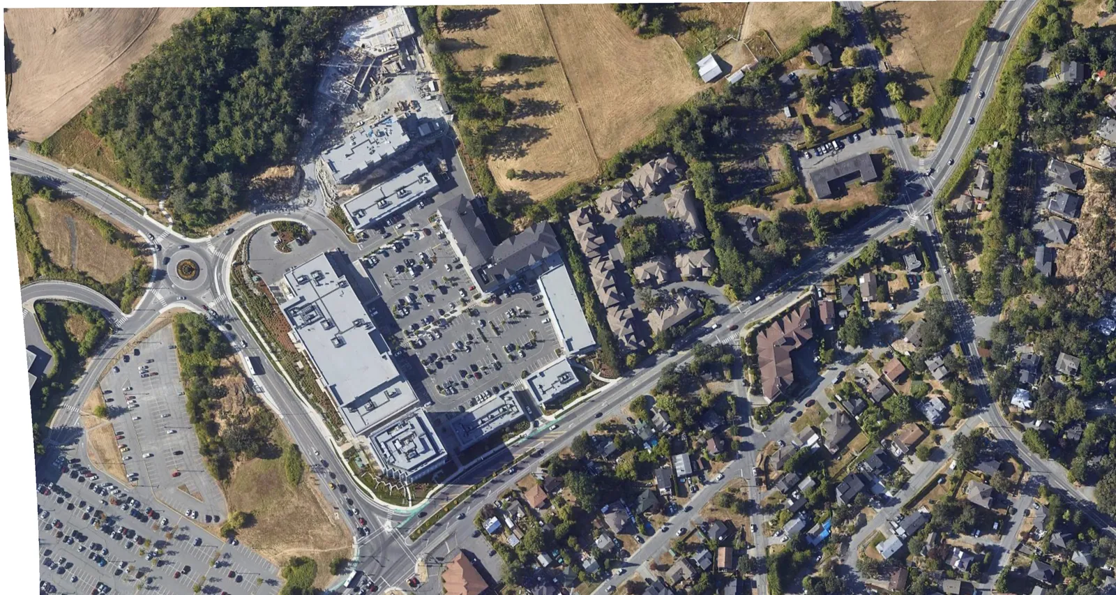 Aerial photograph showing the context of the development site within the surrounding neighborhood, featuring nearby commercial and residential areas.