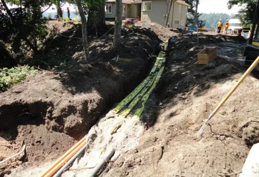 Long trench excavated for services showing yellow underground utility tape