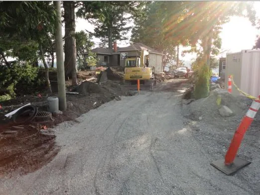 Construction area with a gravel surface, excavators, and orange safety cones