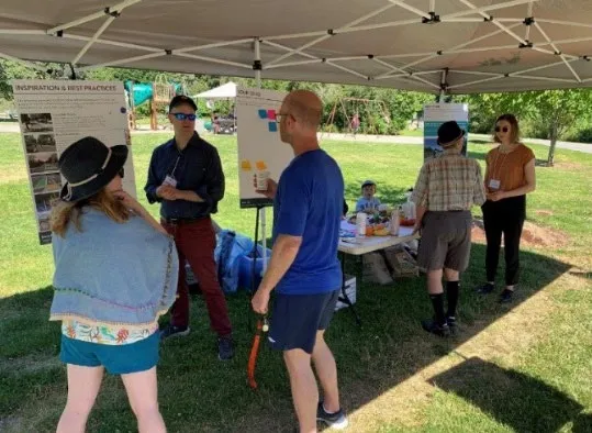 Staff and public at an Ideas Fair event under a tent at Portage Park