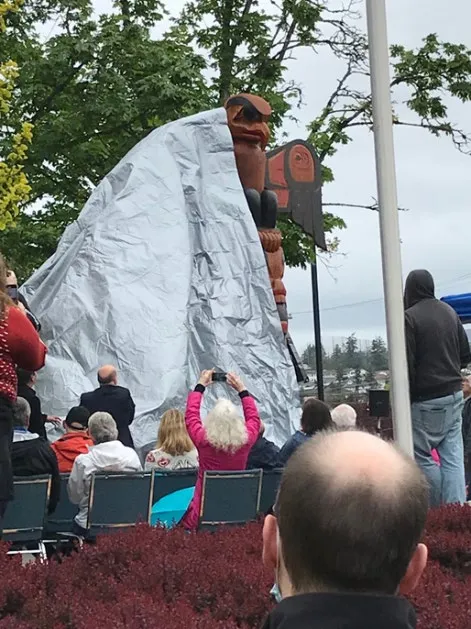 Totem pole covered by a tarp during the unveiling ceremony