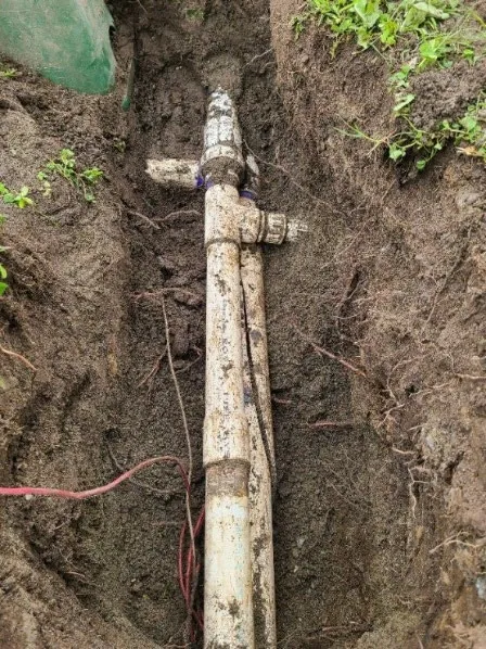 Excavated area showing a repair being made to a large irrigation pipe