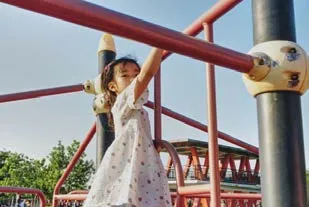 A child playing on a red metal jungle gym at a playground